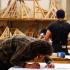 Un apprenti fait des mesures sur un plan sur son atelier