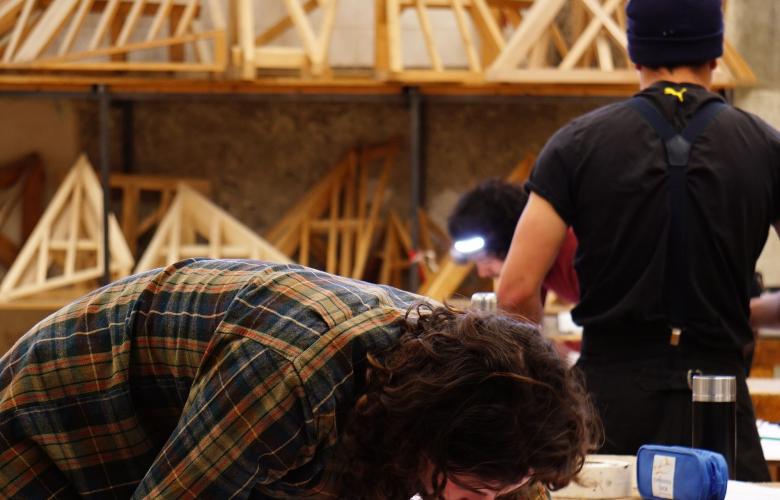 Un apprenti fait des mesures sur un plan sur son atelier