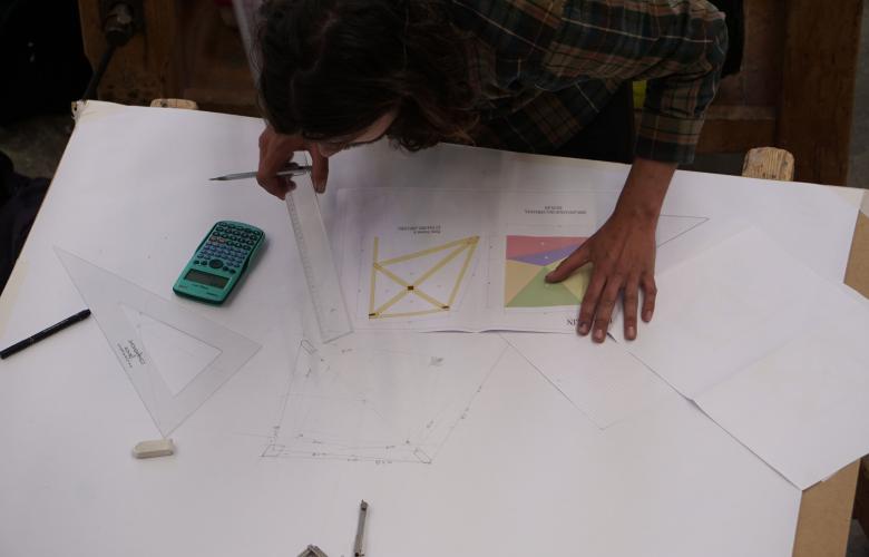 Un apprenti charpentier prend des mesures sur un plan